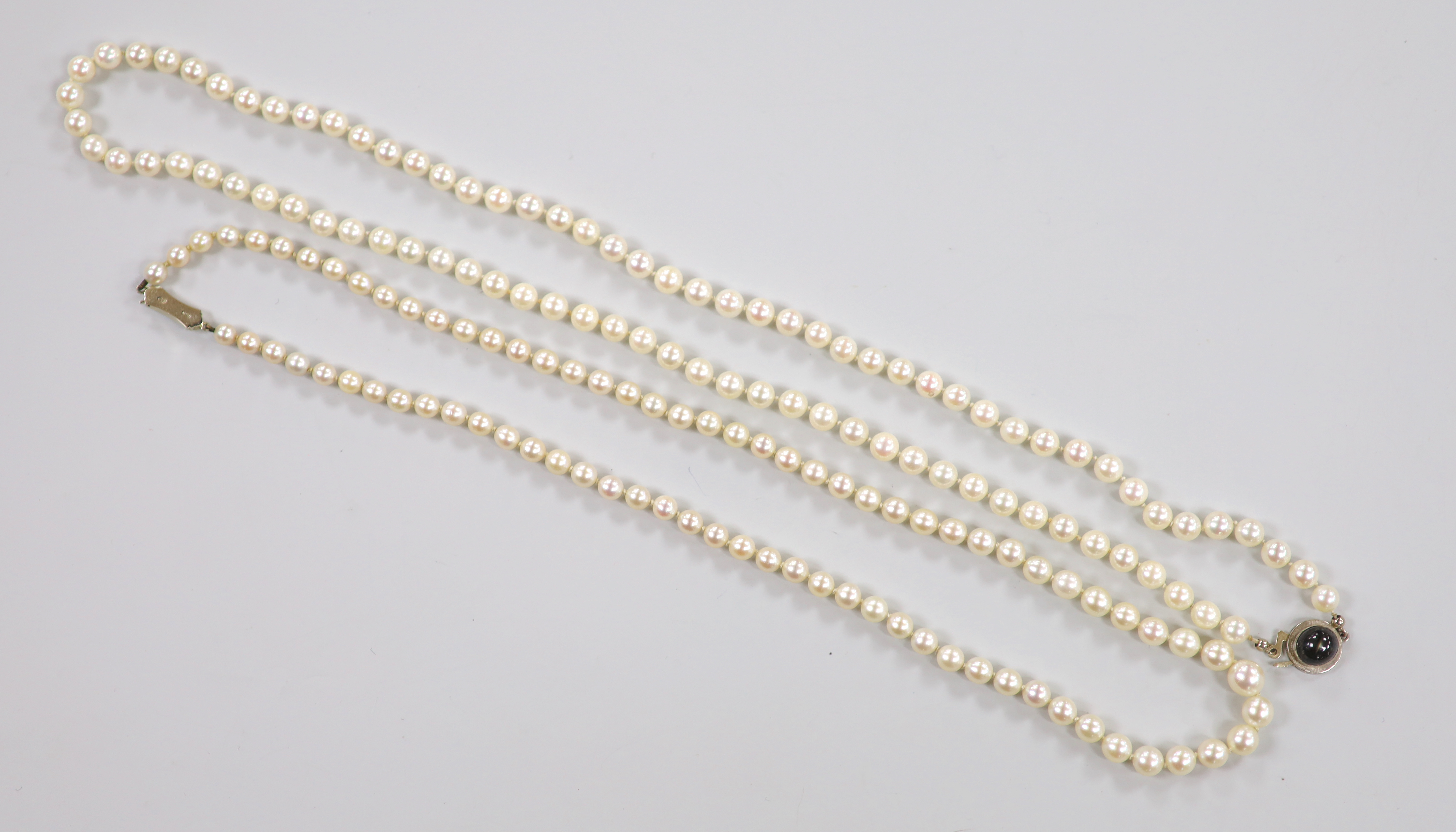 Two modern single strand cultured pearl necklaces, both with 750 white metal clasps, one with star sapphire, longest 62cm.